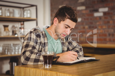 Hipster having coffee and writing in planner
