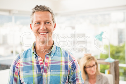 Smiling casual businessman in front of his colleague