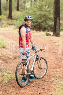 Happy handsome biker holding bike and looking at camera