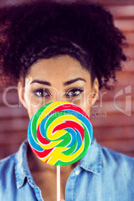 Portrait of a beautiful woman hiding behind a giant lollipop