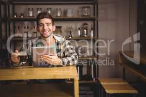 Smiling hipster having coffee and holding tablet computer