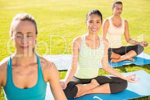 Smiling sporty woman doing yoga with her friends