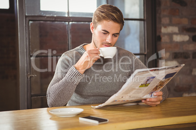 Handsome man drinking coffee and reading newspaper Handsome man drinking coffee and reading newspaper