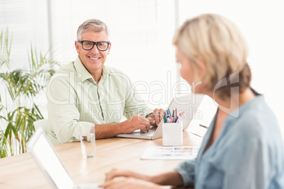 Smiling business team working on laptops