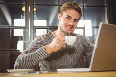 Handsome man smiling and drinking coffee