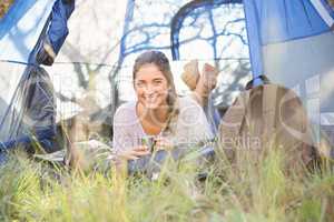 Smiling brunette camper lying in tent