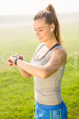 Smiling sporty blonde using smart watch