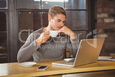 Handsome man drinking coffee and concentrating on laptop Handsome man drinking coffee and concentrating on laptop
