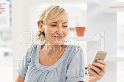 Smiling businesswoman sending a text