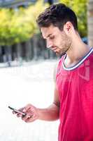 Handsome athlete sending a text