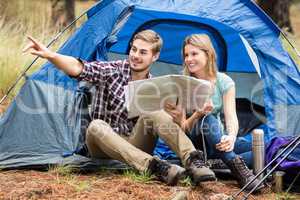 Young pretty hiker couple sitting in a tent pointing