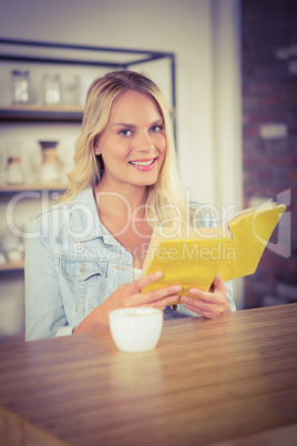 Smiling blonde holding yellow book