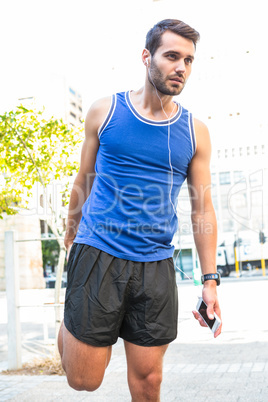 Handsome athlete stretching his leg