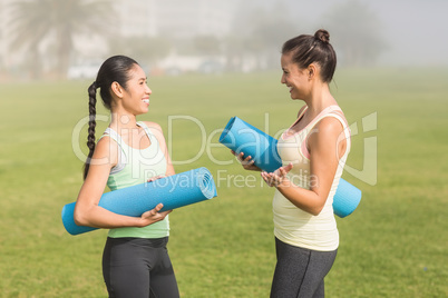 Sporty women with exercise mats chatting
