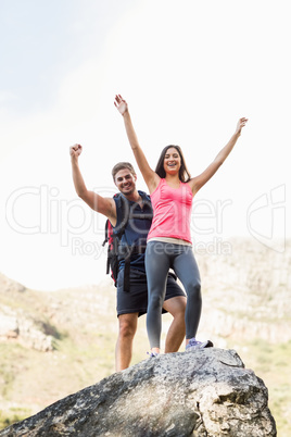 Young happy joggers standing on rock cheering