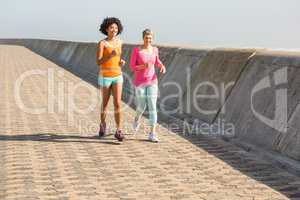 Two smiling sporty women jogging together