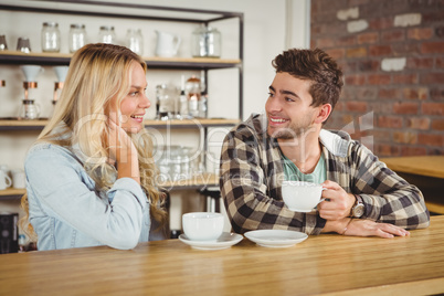 Smiling hipsters sitting and enjoying coffee together