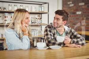 Smiling hipsters sitting and enjoying coffee together