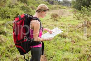Blonde hiker with backpack reading map