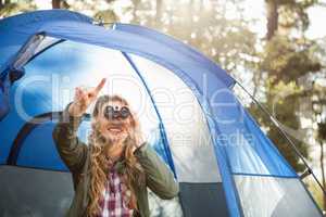 Smiling blonde camper looking through binoculars