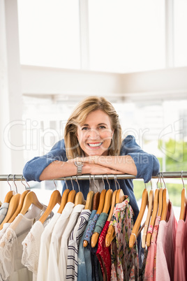 Smiling woman leaning on clothes rail