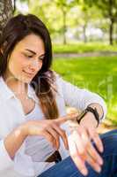 Beautiful brunette using smartwatch in the park