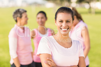 Smiling brunette wearing pink for breast cancer in front of frie