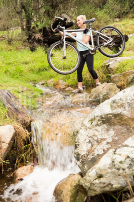 Smiling fit woman lifting her bike