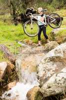 Smiling fit woman lifting her bike