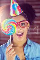 Portrait of a surprised hipster hiding herself behind a lollipop