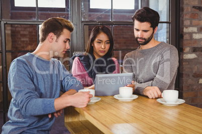 Group of friends enjoying a coffee with a tablet