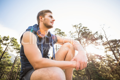 Young happy jogger sitting on rock and looking away