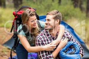 Young pretty hiker couple holding a sleeping bag and backpack