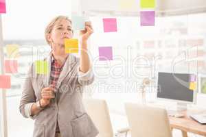 Casual businesswoman writing on sticky notes
