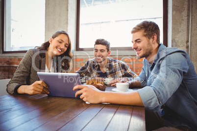 Smiling friends holding tablet and looking at it