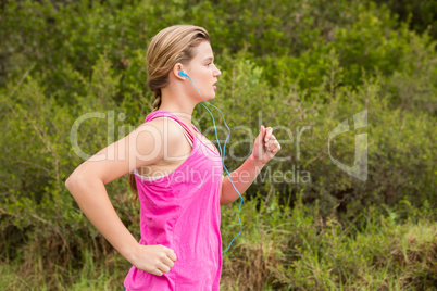 Pretty blonde athlete jogging and listening to music
