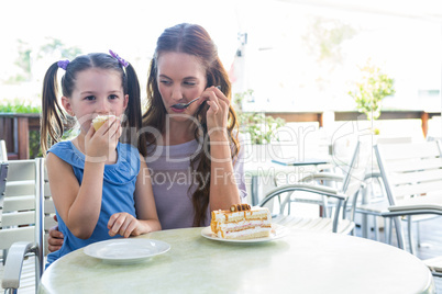 Mother and daughter enjoying cakes at cafe terrace