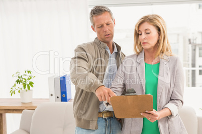 Casual business colleagues looking at clipboard