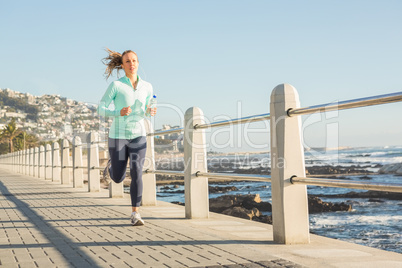 Focused fit blonde jogging at promenade