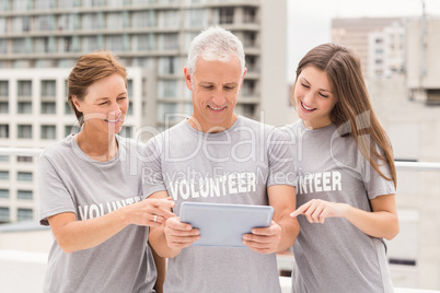 Smiling volunteers using tablet together