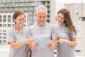 Smiling volunteers using tablet together