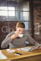 Handsome man drinking coffee and reading newspaper