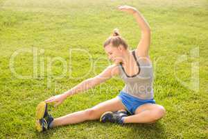 Smiling sporty blonde stretching legs