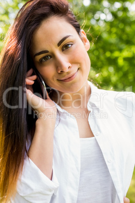 Beautiful brunette in the park making a call