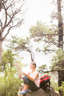 Blonde hiker sitting on rock and reading map