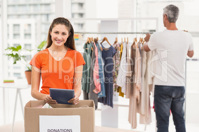 Casual businesswoman with donation box and tablet