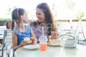 Mother and daughter enjoying cakes at cafe terrace