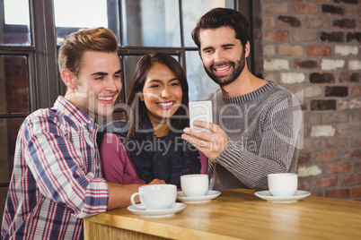 Group of friends taking selfies with a smartphone