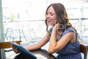 Woman having coffee and using her tablet