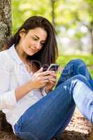 Beautiful brunette sending text in the park